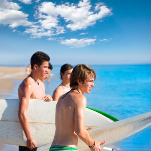 Surfer teen boys talking on beach shore